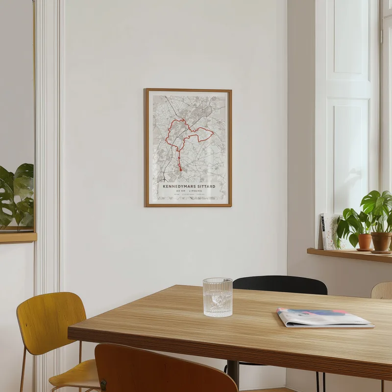 Routeposter van de Kennedymars Sittard in een kamer, boven een houten tafel bij het raam