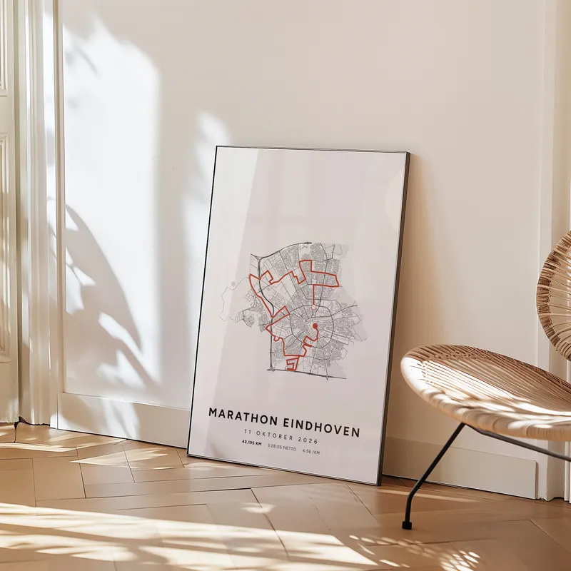 Routeposter van de Marathon Eindhoven in een kamer, tegen de muur op een visgraatvloer, naast een rieten stoel