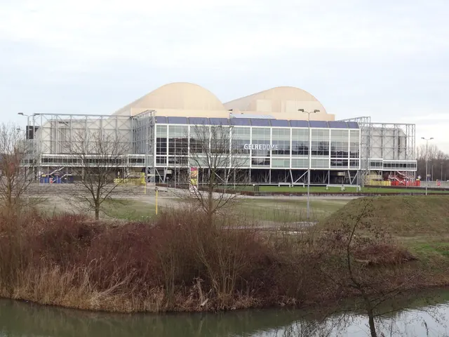 Het GelreDome van opzij, met water en riet op de voorgrond