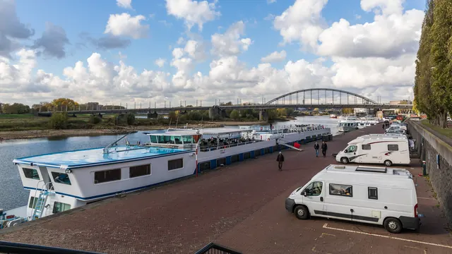 De Rijnkade met campers en rivierschepen, en de John Frostbrug in de verte