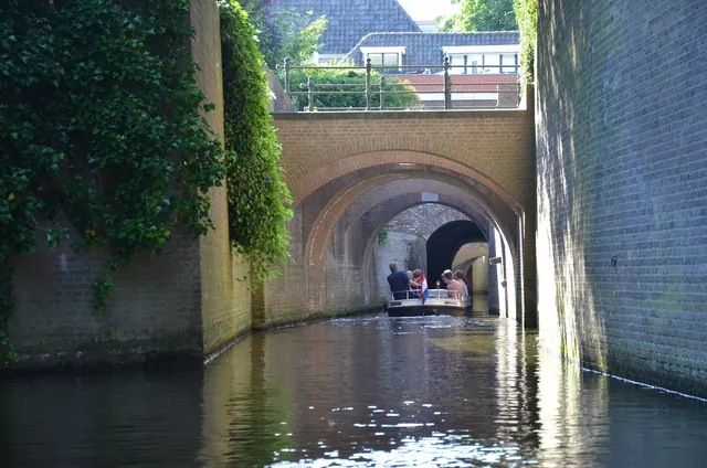 Een boot op de Binnendieze, tussen hoge muren en onder stenen bogen