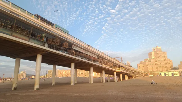 De Scheveningse pier op palen boven het strand, met de flats aan de boulevard erachter