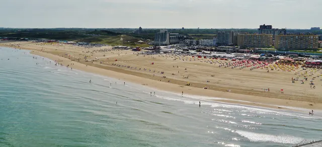 Het strand van Scheveningen van bovenaf, met de boulevard en de duinen in de verte