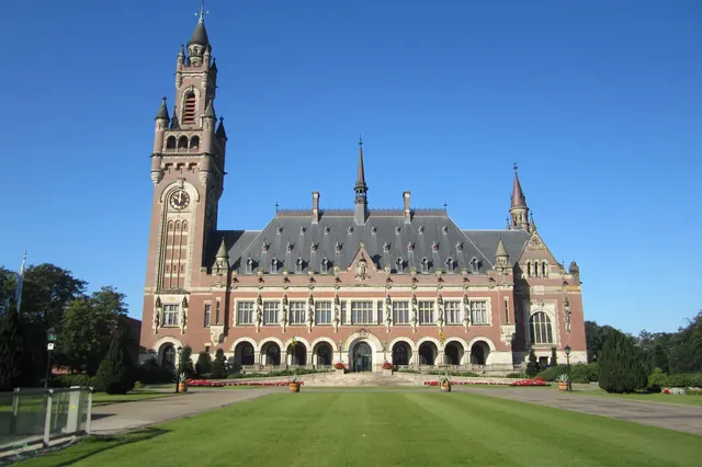Het Vredespaleis met zijn klokkentoren, gezien over het gazon aan de voorkant