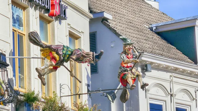 Gevels aan het Stratumseind, met twee beelden van heksen op een bezem