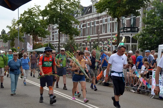 Wandelaars met gladiolen op de Sint Annastraat, op weg naar de finish