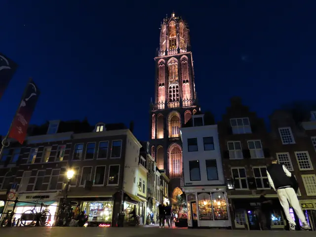 De Domtoren ’s avonds verlicht, boven de gevels van de binnenstad
