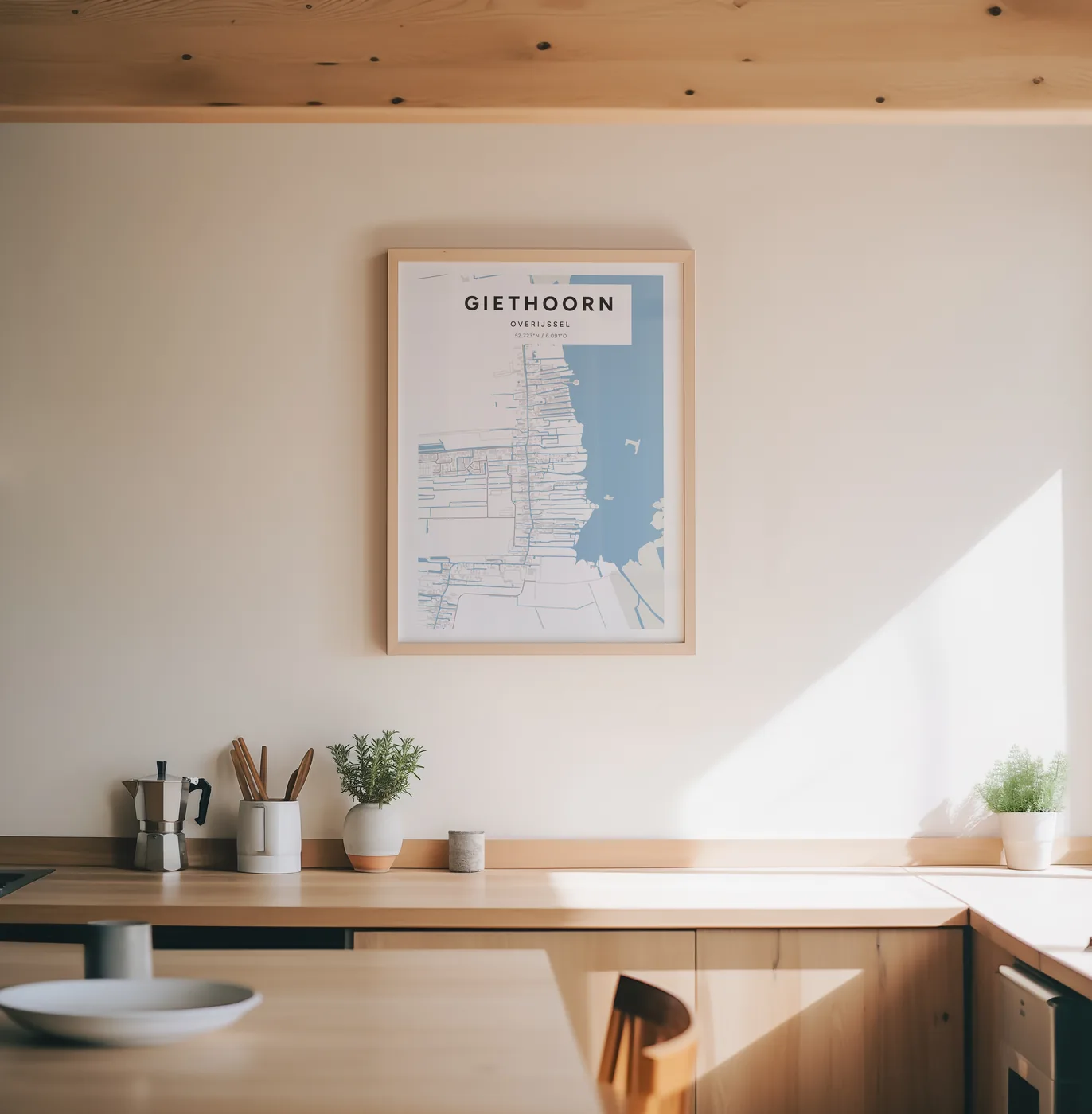De poster van Giethoorn in Steen in een lichte houten lijst aan de muur van een keuken, boven het aanrecht met een koffiepot en kruiden