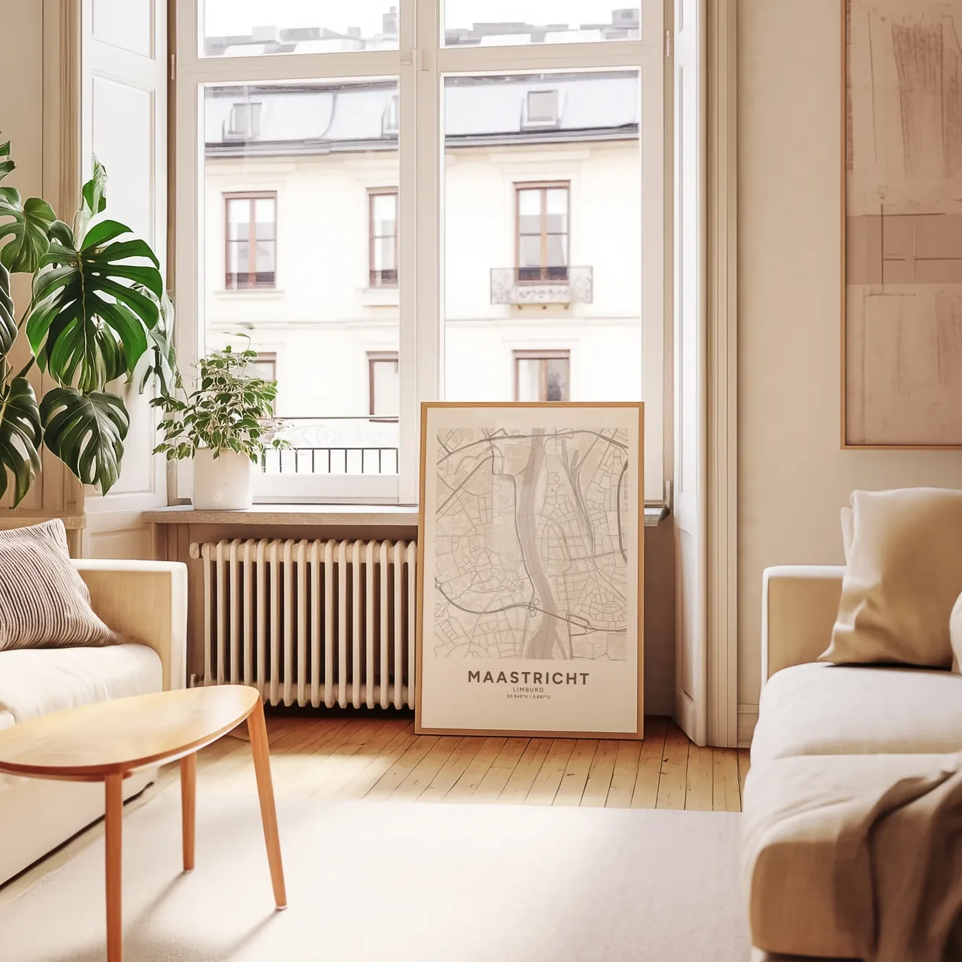 De poster van Maastricht in een lichte lijst op de vloer tegen de muur, in een zonnige kamer met grote ramen